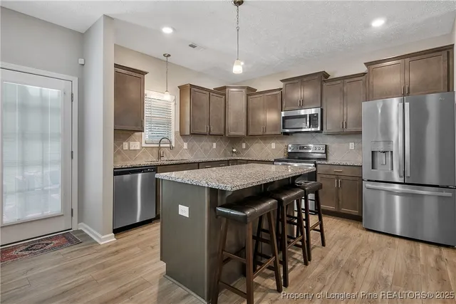 a kitchen with kitchen island granite countertop wooden floor cabinets and stainless steel appliances