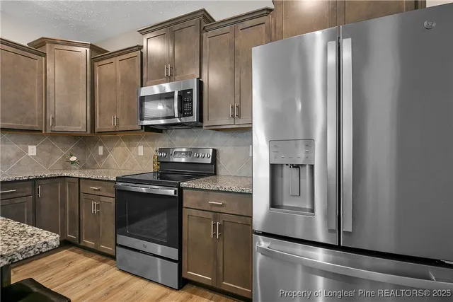a kitchen with stainless steel appliances granite countertop a refrigerator stove and sink