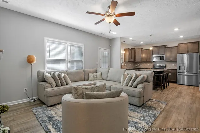 a living room with furniture kitchen view and a window