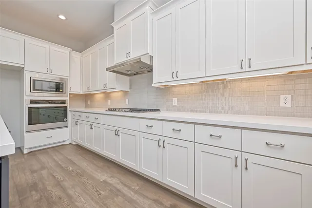 a kitchen with granite countertop white cabinets and stainless steel appliances