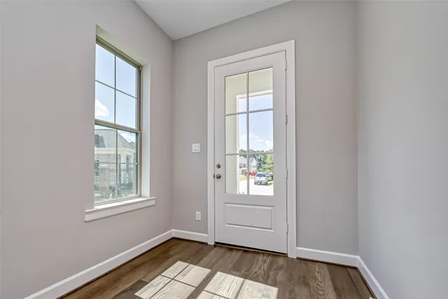 an empty room with wooden floor and windows
