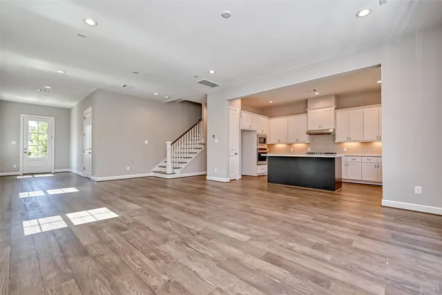 a view of kitchen and empty room with wooden floor