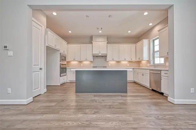 a large kitchen with kitchen island white cabinets and stainless steel appliances