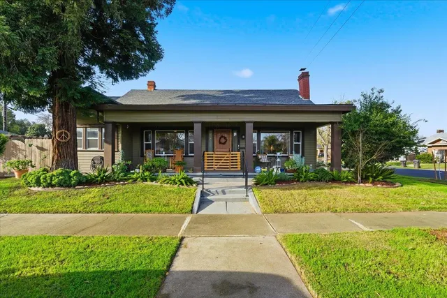 a front view of a house with a yard and potted plants