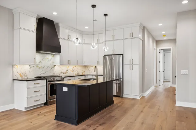 a kitchen with stainless steel appliances granite countertop a sink a stove and a refrigerator