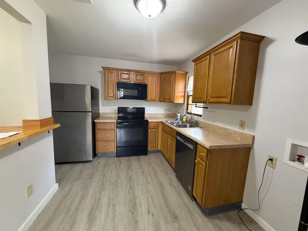 a kitchen with a sink wooden floor and stainless steel appliances