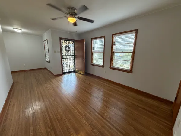 a view of an empty room with wooden floor and a window