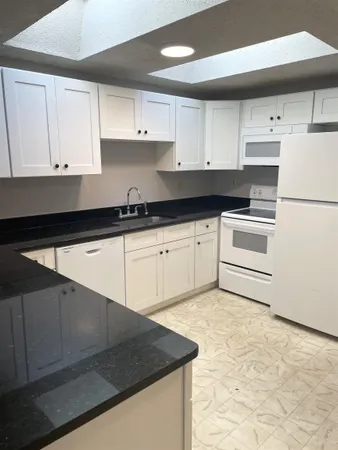 a kitchen with granite countertop a sink a stove and cabinets