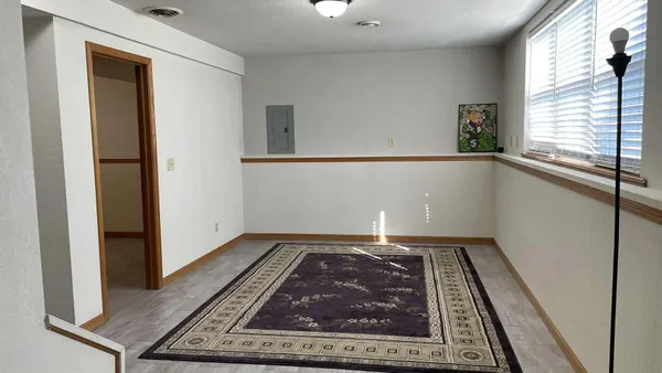 a view of a hallway to an empty room and window