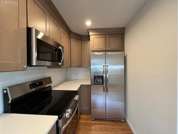 a kitchen with granite countertop stainless steel appliances and wooden floor
