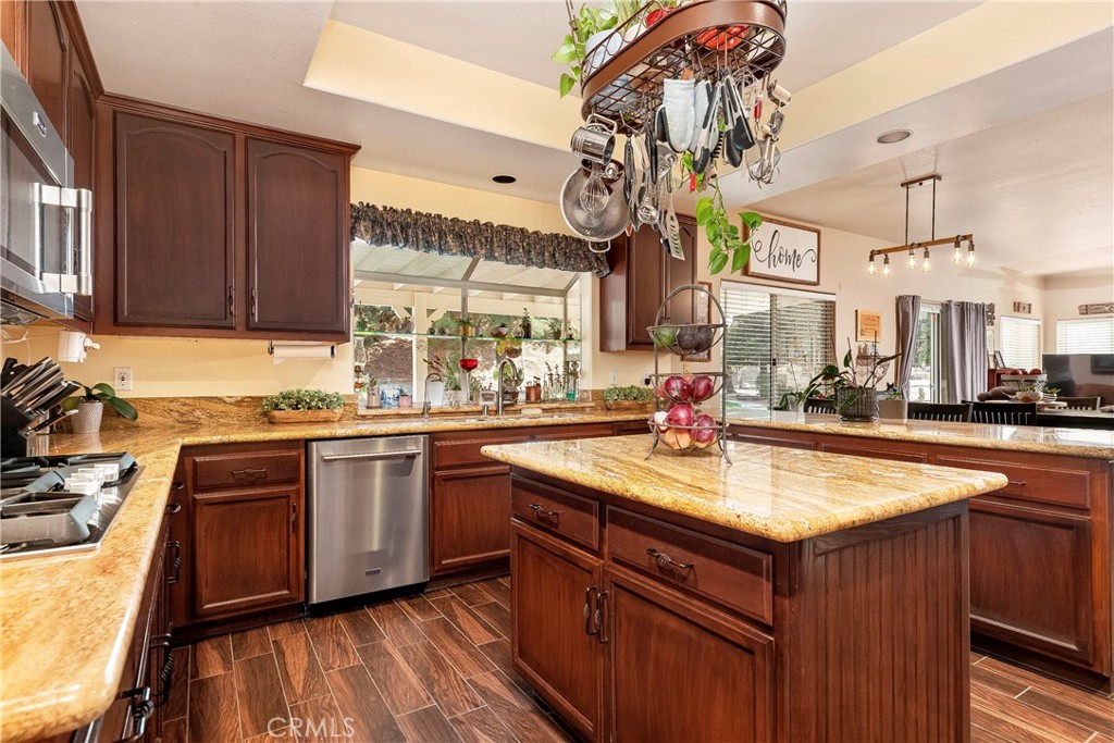 32201 Joaquin Road Acton, CA 93510 - Photo 22 of 75 a kitchen with a sink dishwasher a stove and a dining table with wooden floor