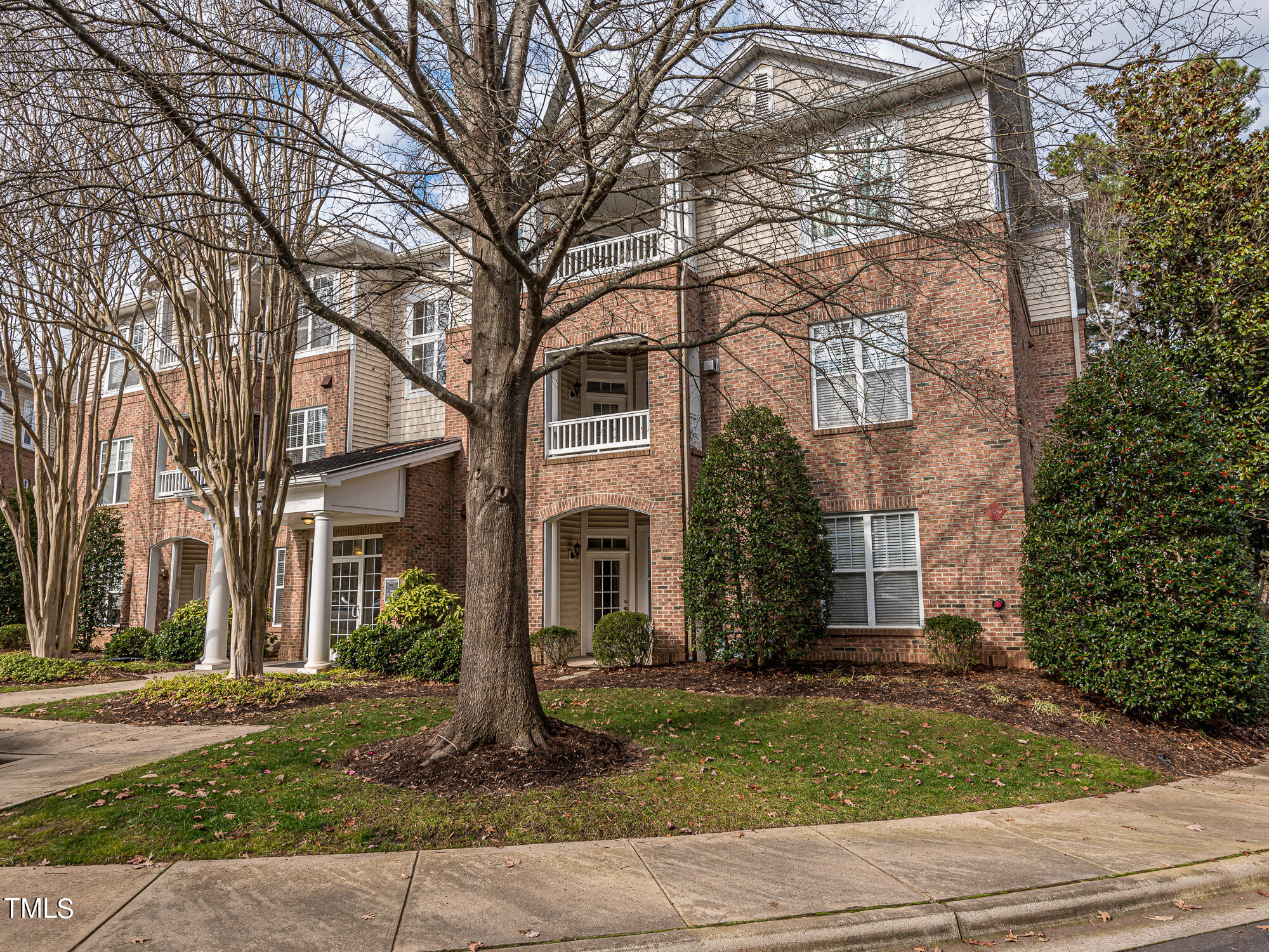 8041 Allyns Landing Way, Unit 103 Raleigh, NC 27615 - Photo 4 of 33 a view of a brick house next to a yard with large trees