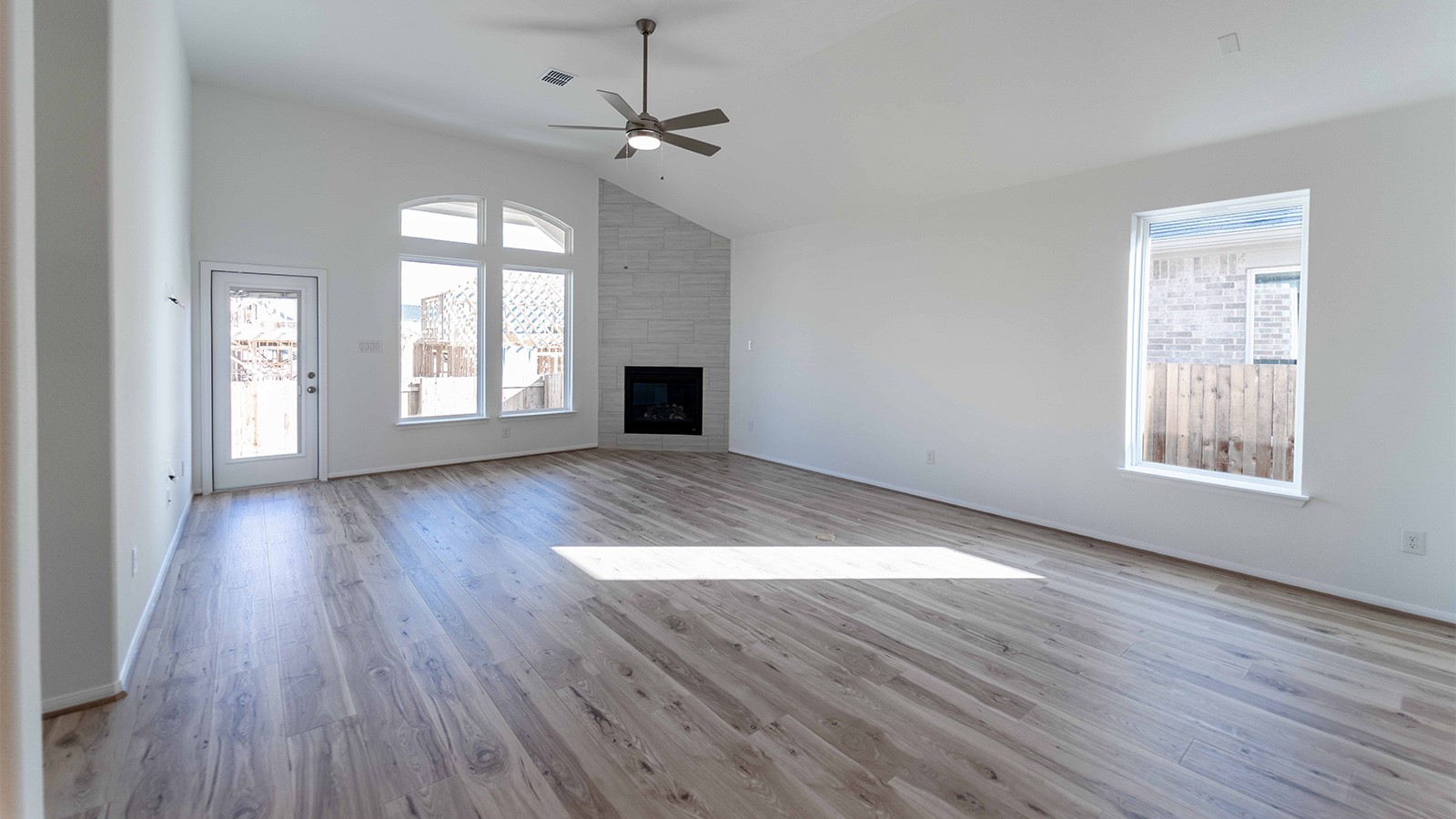 294 Rubber Tree Way Buda, TX 78610 - Photo 2 of 19 Unfurnished living room with vaulted ceiling, light wood-type flooring, a large fireplace, and a ceiling fan