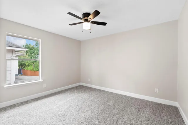 an empty room with a window and a fan