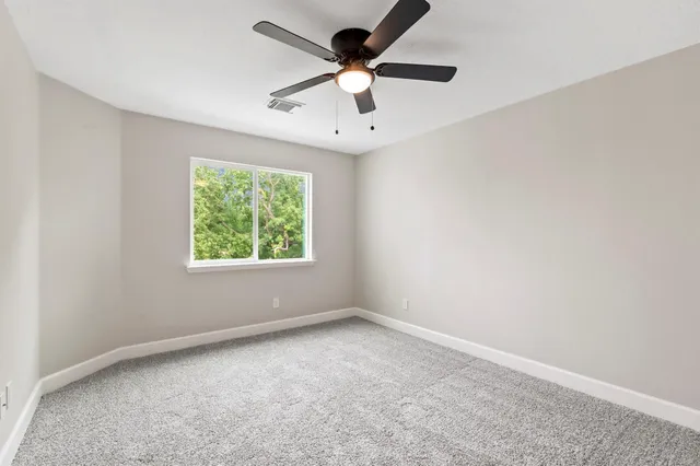 an empty room with a window and a fan