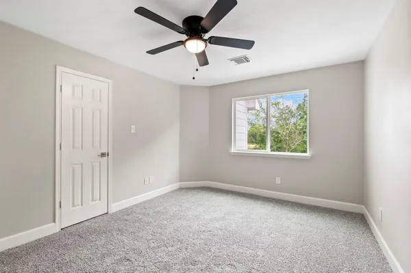 an empty room with windows and ceiling fan