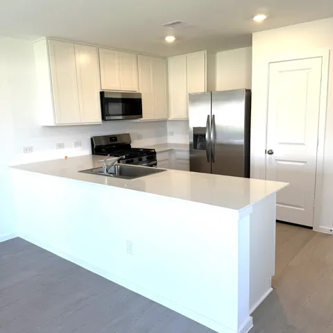 a kitchen with stainless steel appliances a refrigerator a sink a stove a microwave and island