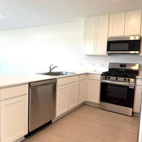 a kitchen with stainless steel appliances a sink dishwasher a stove and white cabinets