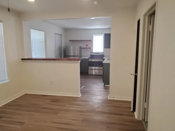 a kitchen with a refrigerator a stove top oven a sink and a wooden floor