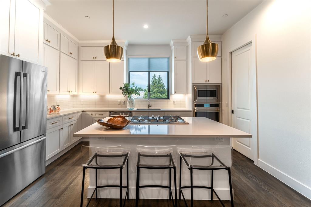 13900 Noel Road, Unit 202 Dallas, TX 75240 - Photo 4 of 11 a kitchen with a table chairs refrigerator and microwave