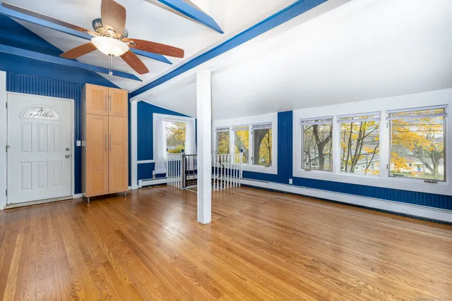 a view of empty room with wooden floor and fan