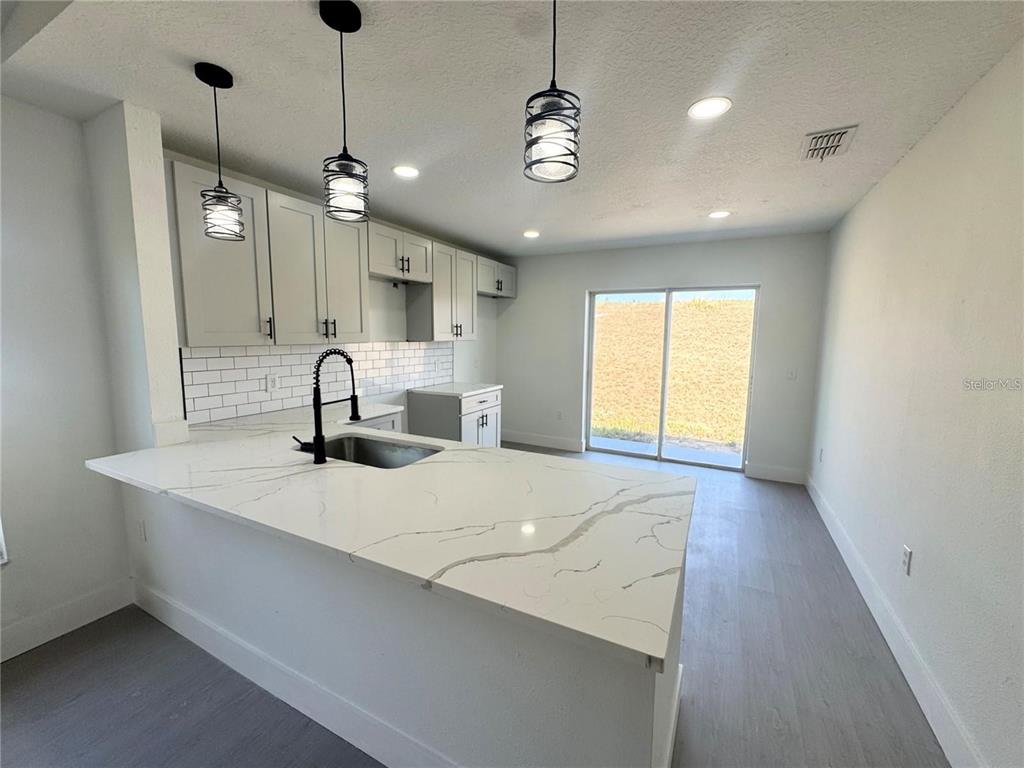 207 High Ridge Drive Davenport, FL 33837 - Photo 6 of 33 a large kitchen with stainless steel appliances a large window a sink and a chandelier