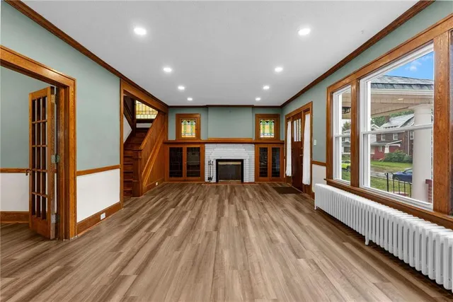 an empty room with wooden floor fireplace and windows