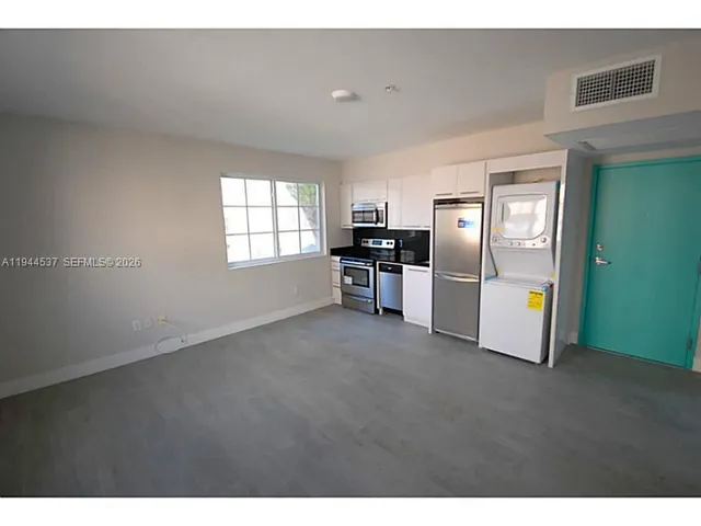 a view of empty room with window and refrigerator