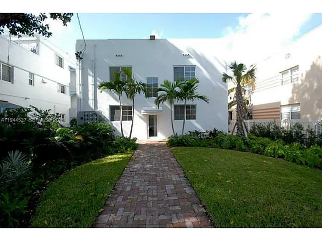 a front view of a house with a yard and potted plants