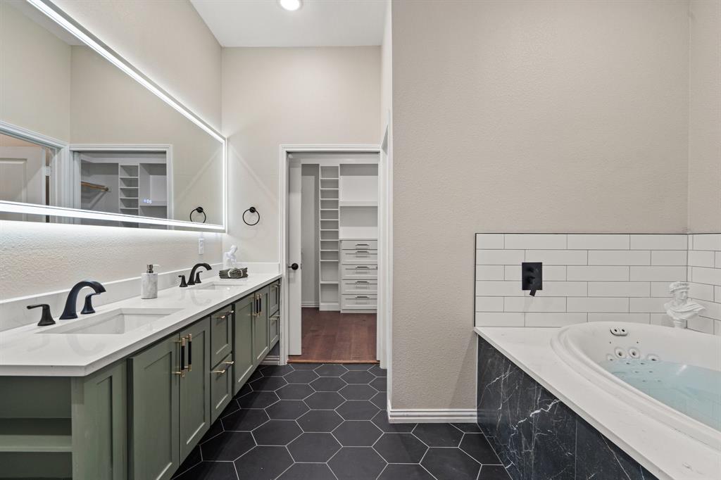 2514 Carpenter Avenue Dallas, TX 75215 - Photo 16 of 24 a bathroom with a double vanity sink a mirror and a bathtub