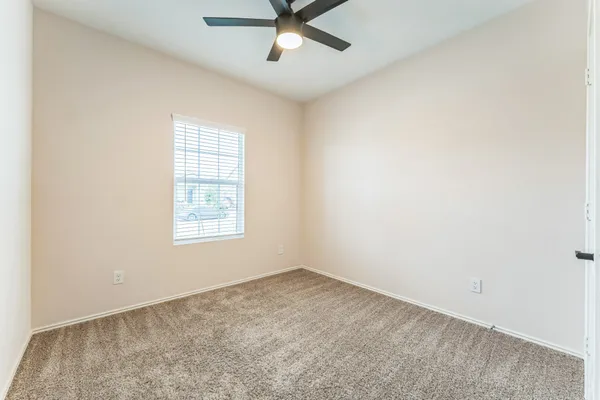 an empty room with a window and a fan