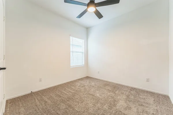 an empty room with a window and a ceiling fan