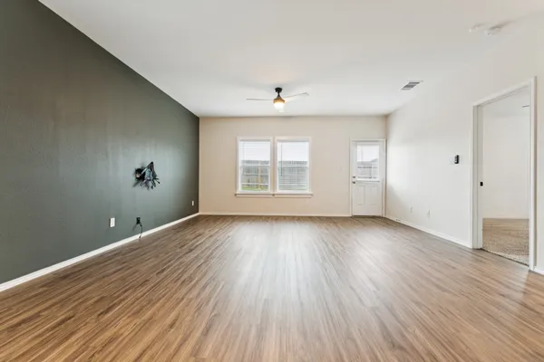 an empty room with wooden floor and windows