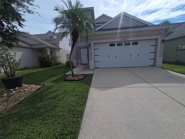 a view of a house with a yard and a large tree
