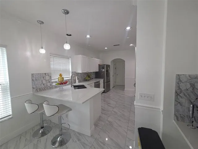 a kitchen with stainless steel appliances kitchen island granite countertop a sink and a refrigerator