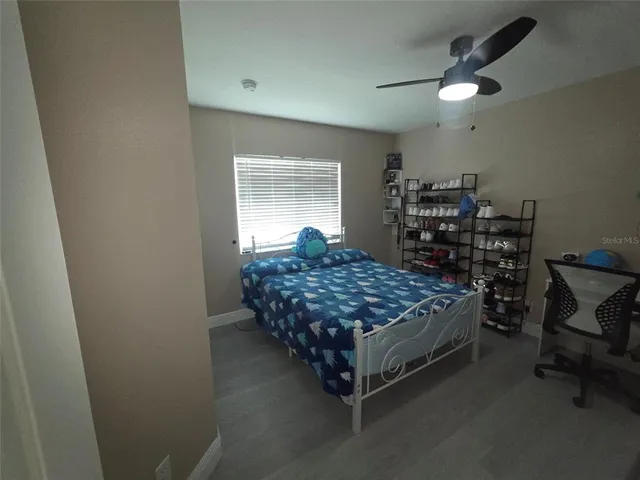 a bedroom with a bed a desk and chair with wooden floor