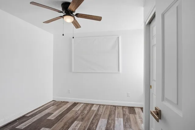 a view of room with hardwood floor and a ceiling fan