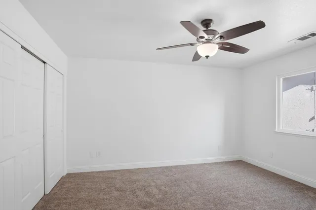an empty room with window and ceiling fan
