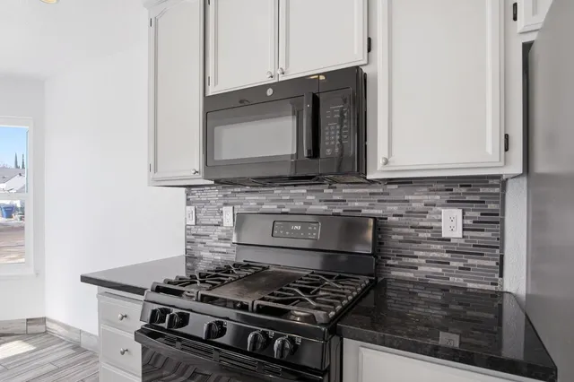 a kitchen with granite countertop a stove top oven microwave and cabinets