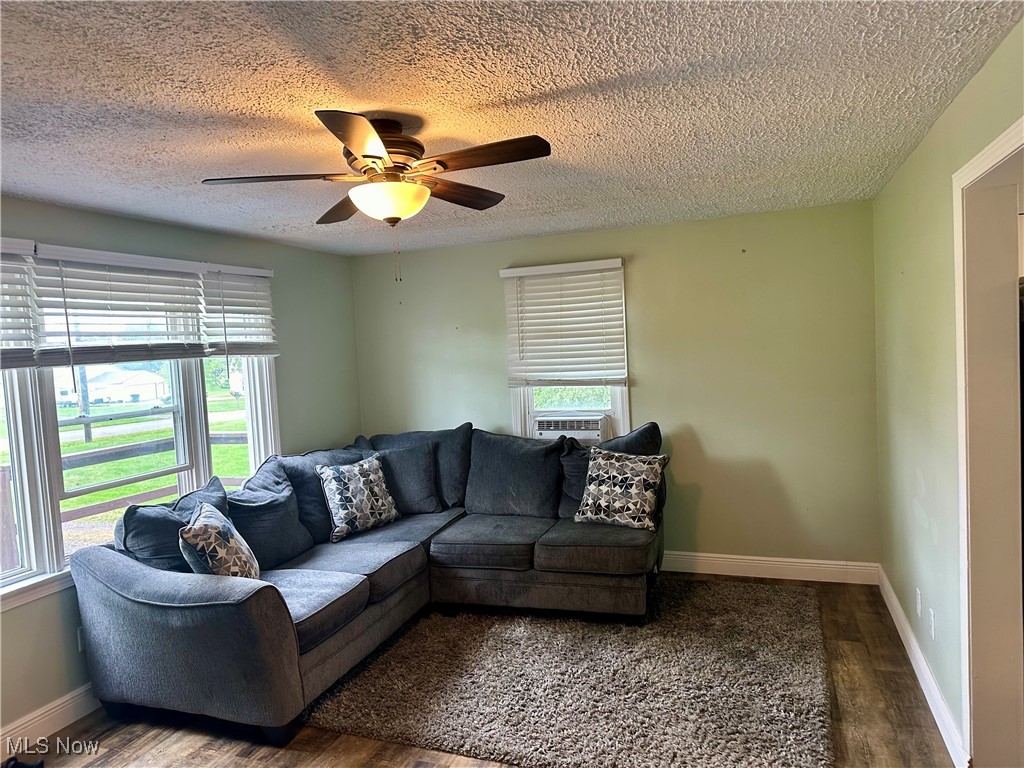 4664 Kennedy Road Lowellville, OH 44436 - Photo 2 of 11 Living room featuring wood-type flooring, cooling unit, ceiling fan, and a textured ceiling