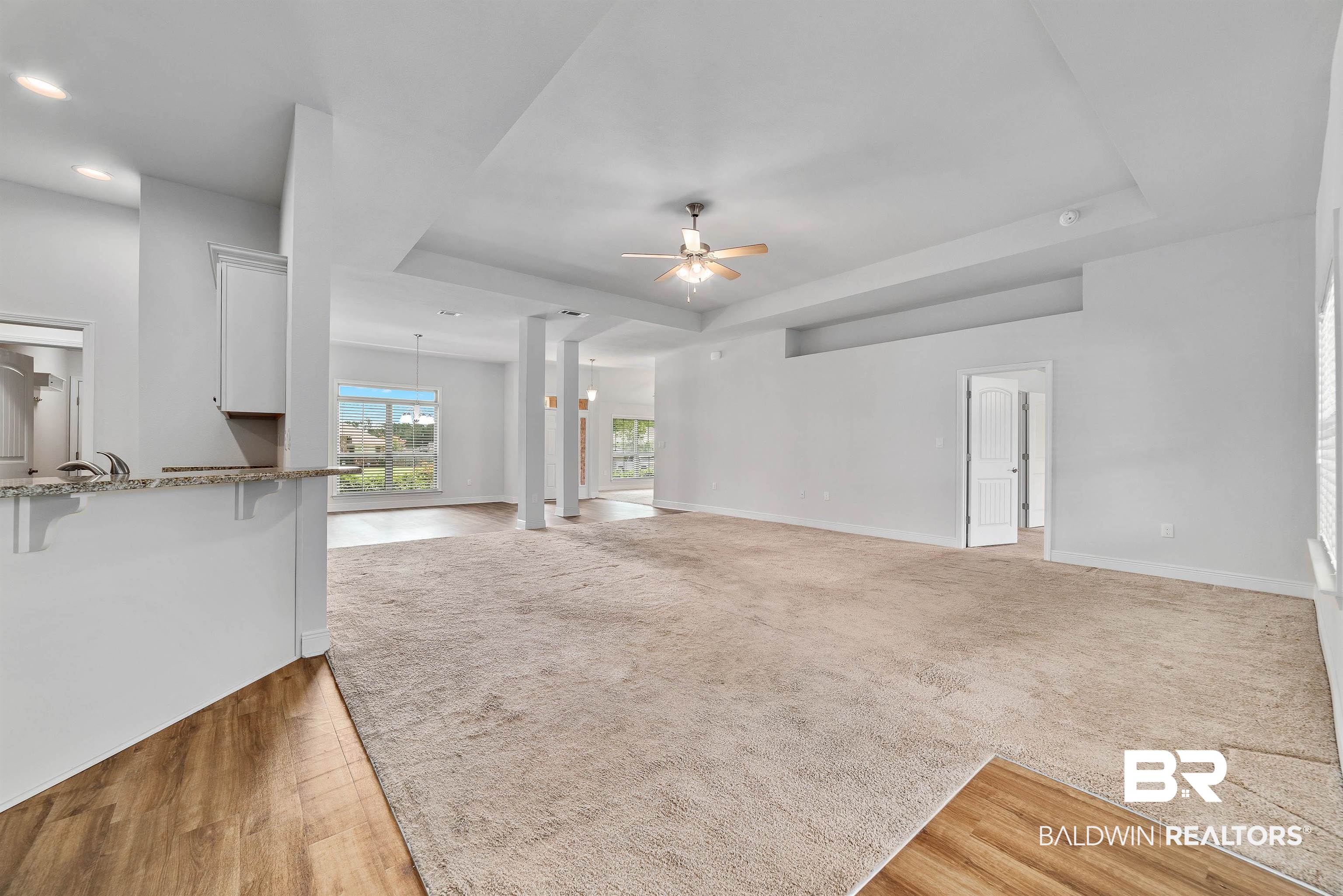 13155 Wishbone Court Foley, AL 36535 - Photo 12 of 39 Unfurnished living room with a tray ceiling, light hardwood / wood-style floors, ornate columns, and ceiling fan