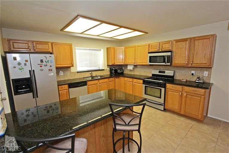 1025 Roldan Avenue Simi Valley, CA 93065 - Photo 5 of 28 a kitchen with stainless steel appliances granite countertop a stove a sink a microwave a refrigerator dining table and chairs