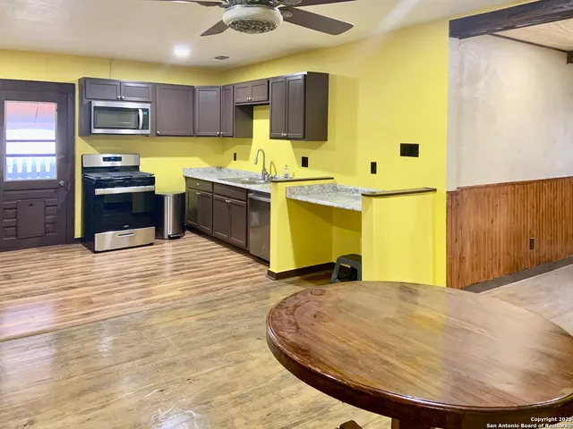 a view of kitchen with stainless steel appliances wooden cabinets and living room view