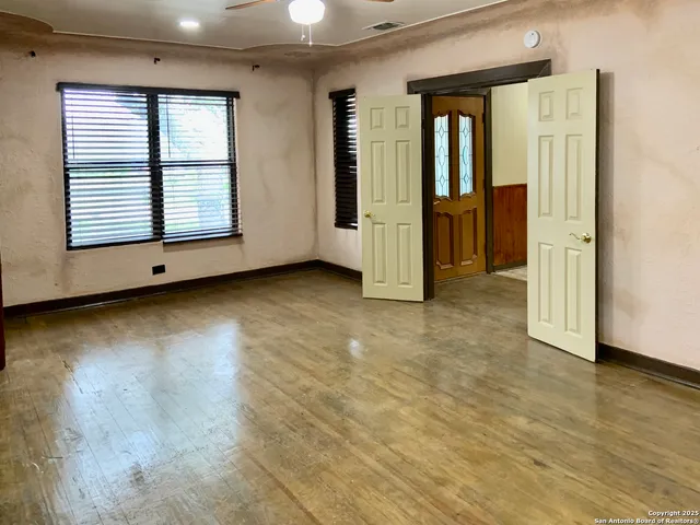 an empty room with wooden floor and windows