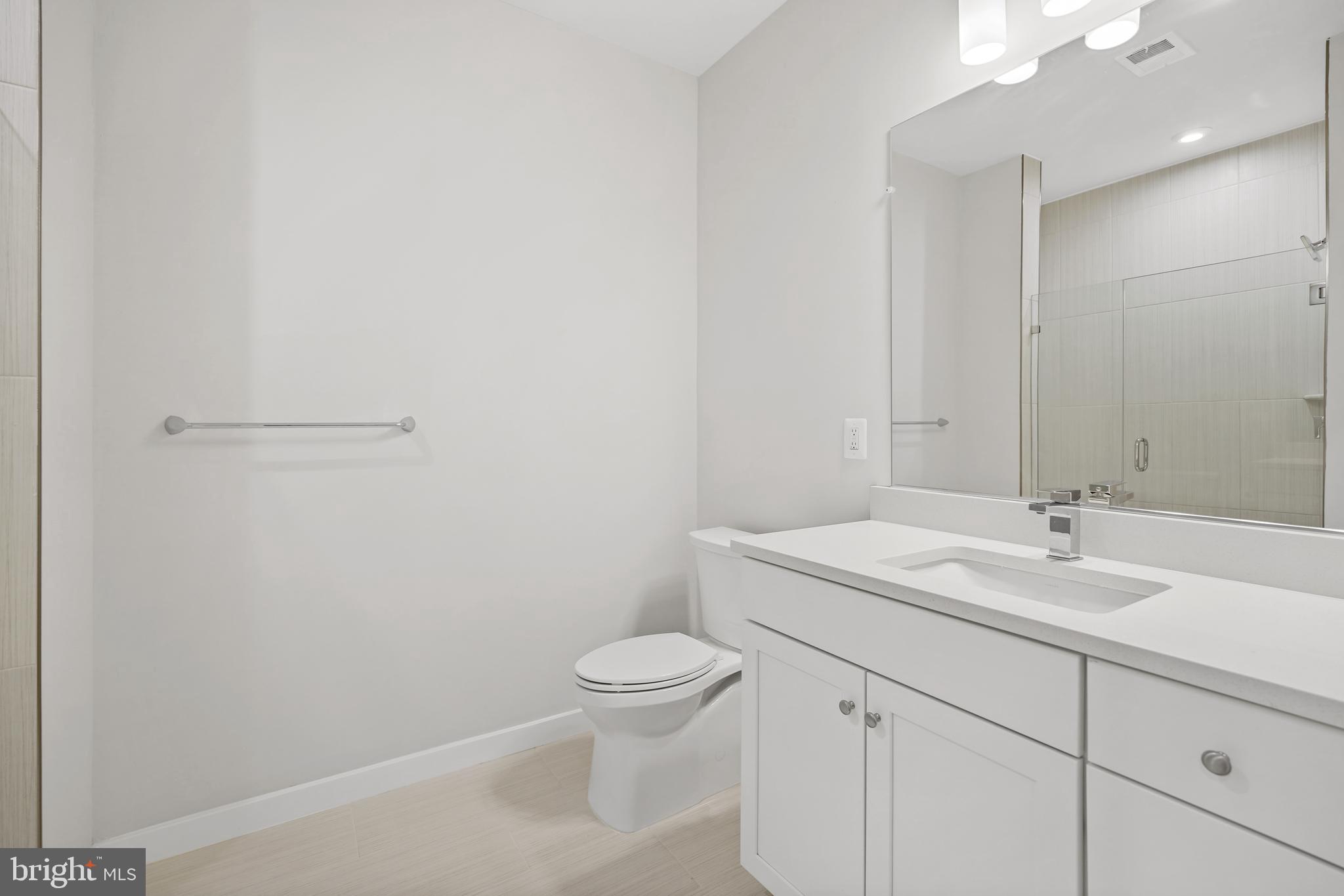 1675 Bandit Loop, Unit 107B Reston, VA 20190 - Photo 15 of 36 a bathroom with a granite countertop sink a toilet and a mirror