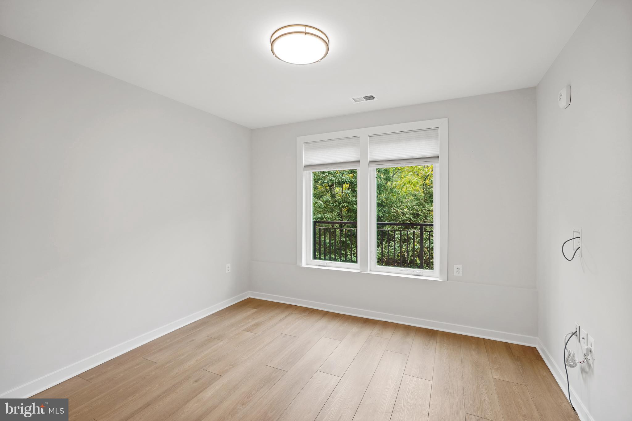 1675 Bandit Loop, Unit 107B Reston, VA 20190 - Photo 17 of 36 an empty room with wooden floor and windows