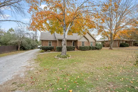 a front view of a house with a yard and trees