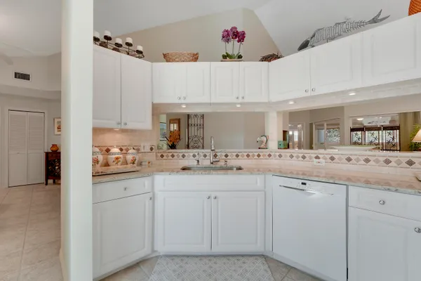 a kitchen with white cabinets and sink