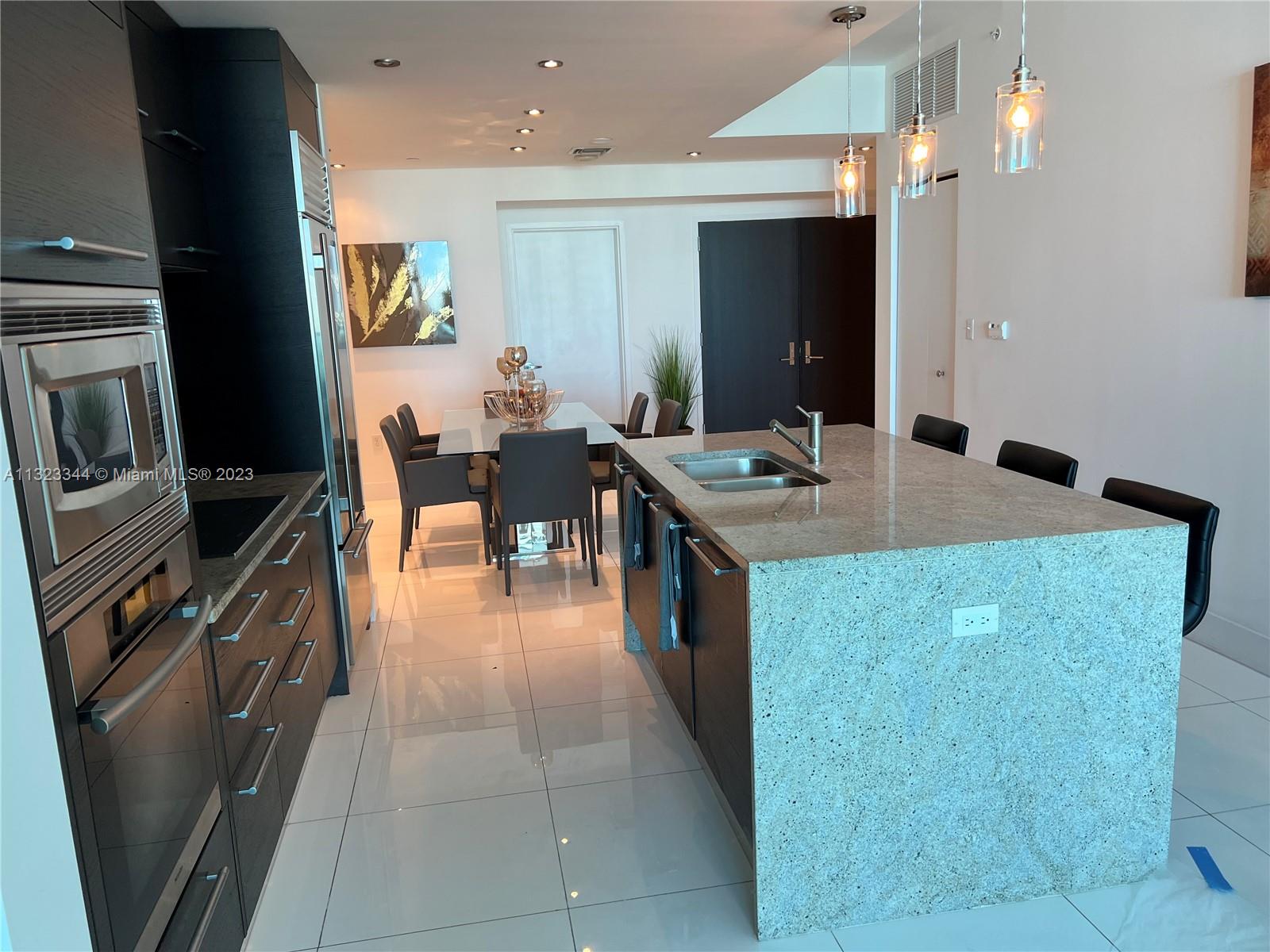 a kitchen with kitchen island granite countertop a sink counter top space and stainless steel appliances