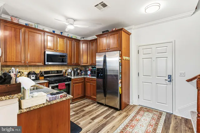 a kitchen with stainless steel appliances granite countertop a refrigerator and a stove top oven